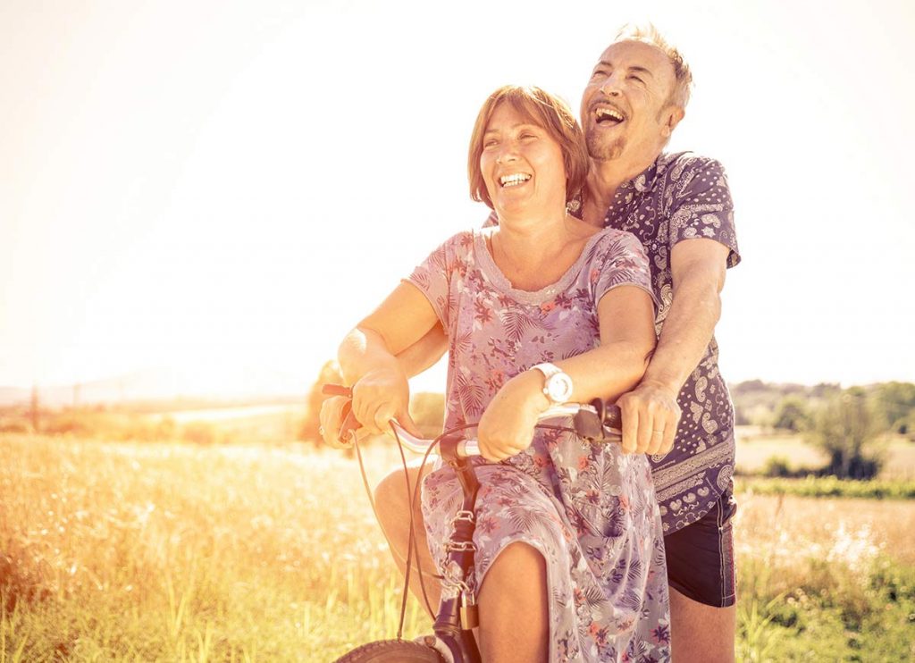 Pareja de adultos mayores felices paseando en bicicleta juntos